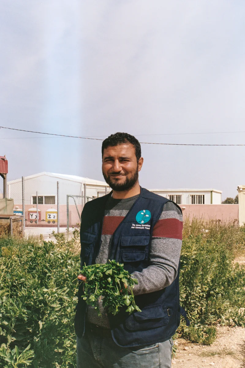 Azraq Center faculty member holding fresh produce he grew for the kids.